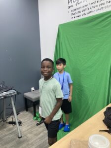 2 kids smile in front of green screen