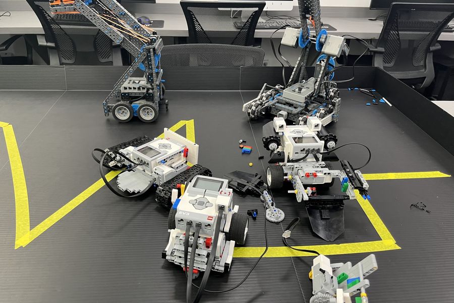 VEX and LEGO robots built by students on a challenge mat