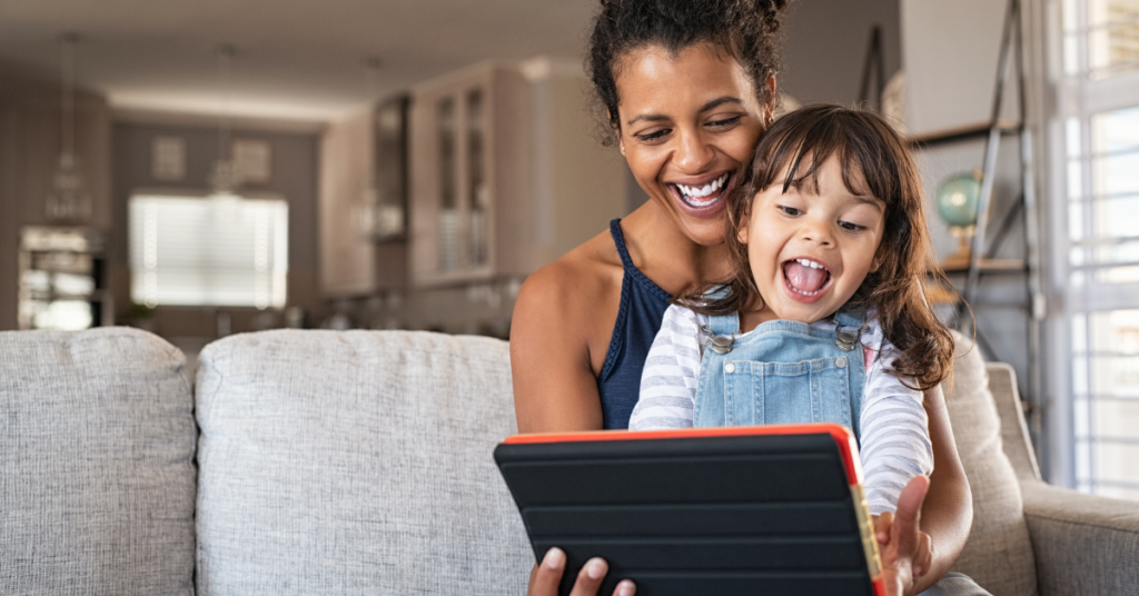 Parent monitoring kids screen time while sitting with child using a tablet at home